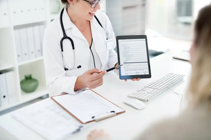 Clinician reviewing lab results on a tablet during a patient consultation