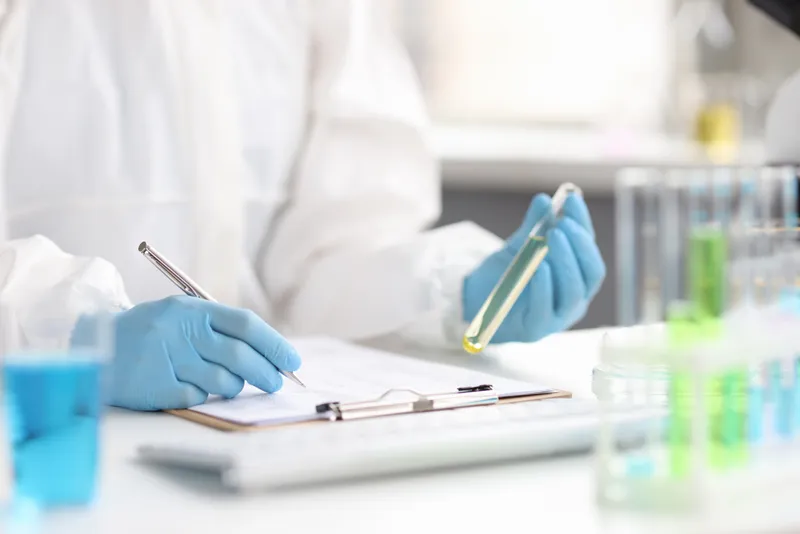 Scientist in a bright lab analyzing samples in test tubes alongside notes