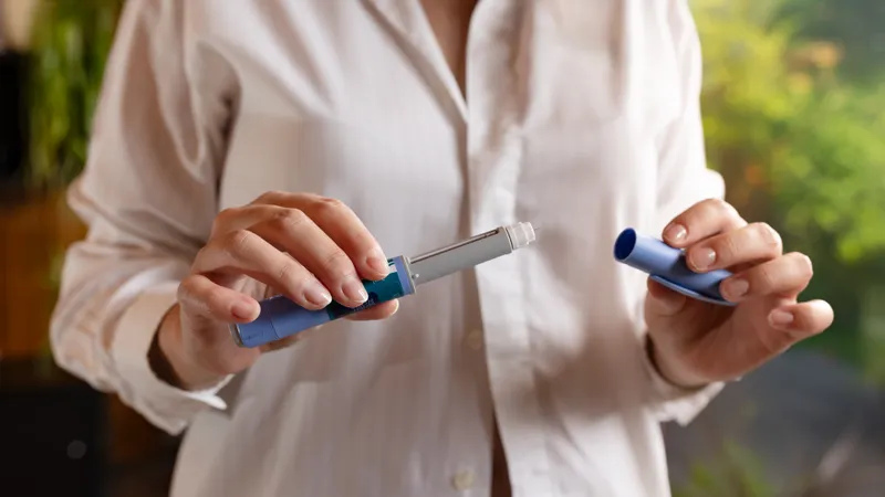Patient at home holding a prescription weight-loss medication pen